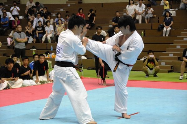 立石（左）は左右の廻し蹴り・鍵突き・下突きで揺さぶりを掛ける。岡田(左)はこれを凌ぎ、縦形の技に加え下段蹴りを有効に使い、一進一退の攻防が展開した。